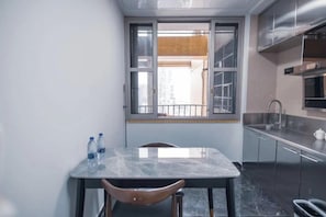 A compact kitchen with a dining table, chairs, a window with a view, and stainless steel appliances. - Jinyuan Projection Apartment (Beijing Road Pedestrian Street Store) (Guangzhou)