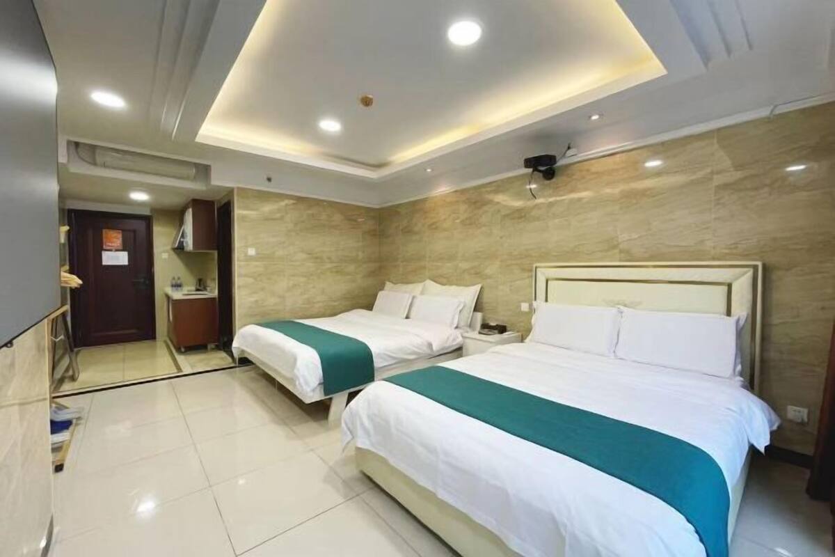 A hotel room with two beds, a nightstand, a mirror, and a door.
