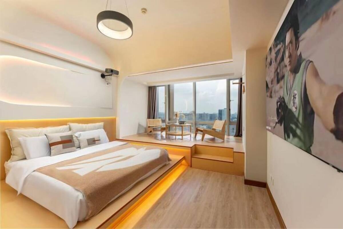 A modern hotel room with a large bed, a desk, and a view of the city.