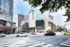 A city intersection with modern buildings, a crosswalk, and vehicles.