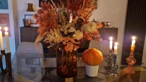 A table with a glass top, a vase with dried flowers, a candle holder, and a candle. - The blue spruce room (Roma)