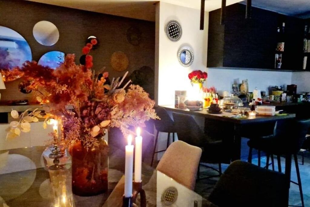 Un'area pranzo moderna con un tavolo in vetro, candele e un vaso di fiori.