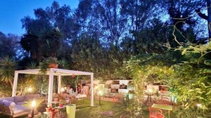 An outdoor patio area with seating arrangements, potted plants, and a pergola structure. - The blue spruce room (Roma)