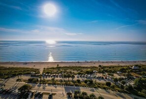 An aerial view of a coastal area with a beach, parking lot, and clear blue sky. - Brand new 3-bedroom house in sunny Port Charlotte. (Port Charlotte)