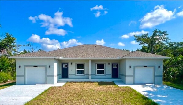 A two-story house with a front garage, a covered porch, and a well-maintained lawn. - Brand new 3-bedroom house in sunny Port Charlotte. (Port Charlotte)