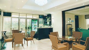 A hotel lobby with wicker furniture, a reception desk, and a bar area with a Heineken refrigerator. - Mamba Residence (Kigali)