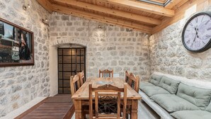 Une pièce rustique aux murs de pierre, avec une table et des chaises en bois, un canapé vert et une grande horloge murale.