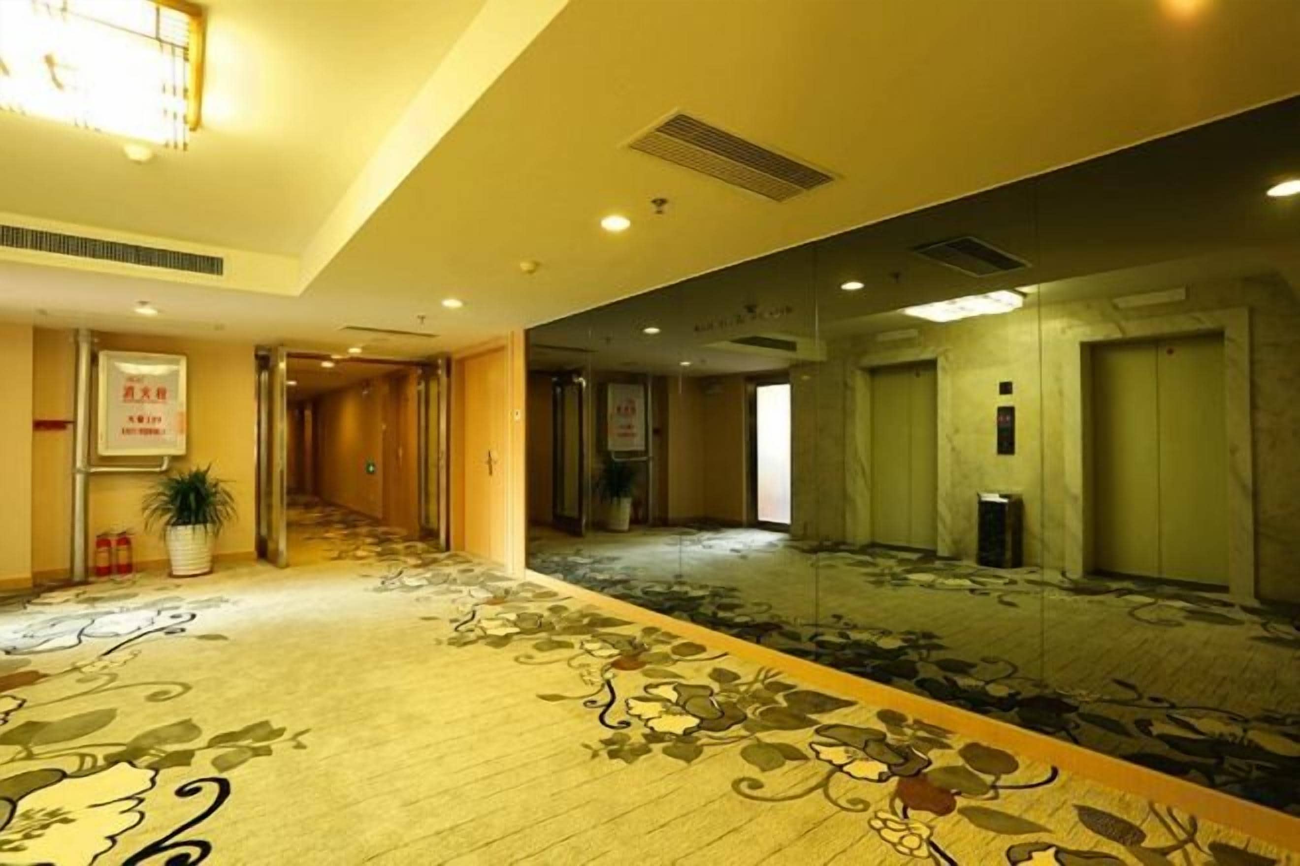 A hotel lobby with a carpeted floor, a reception desk, and a staircase leading to another floor.