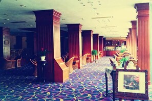 A hotel lobby with a patterned carpet, wooden columns, and seating areas. - Swatow Peninsula Hotel (Shantou)