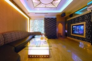 A modern lounge area with a sofa, a glass-top coffee table, and a television screen. - Swatow Peninsula Hotel (Shantou)