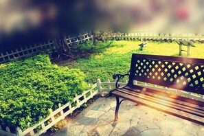 A bench in a park with a white picket fence and greenery. - Swatow Peninsula Hotel (Shantou)