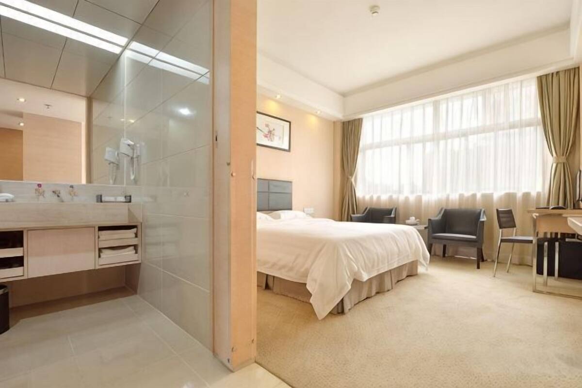 Una habitación de hotel con cama, escritorio, silla, espejo y ventana.