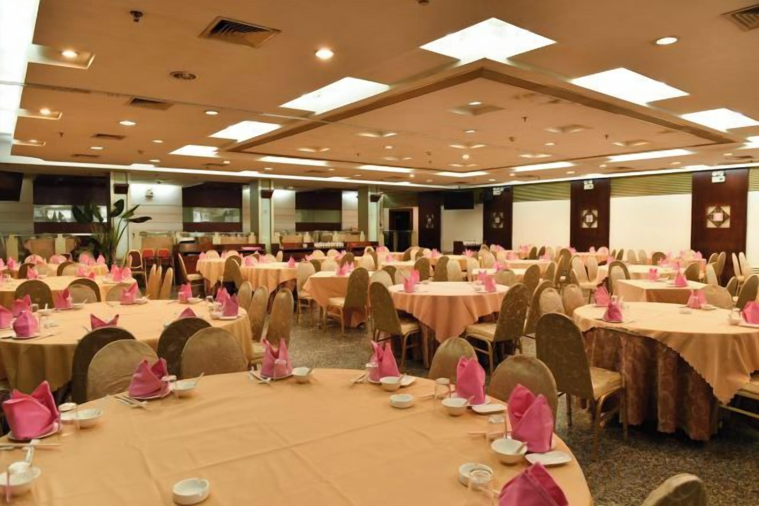 A banquet hall with round tables, chairs, and pink table settings.