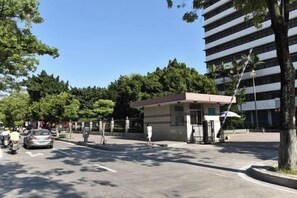 A parking lot with a building, trees, and a clear sky. - Swatow Peninsula Hotel (Shantou)