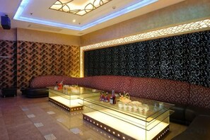Ein moderner Lounge-Bereich mit Wandverkleidung, einer Couch und einem Glastisch mit Gegenständen darauf.