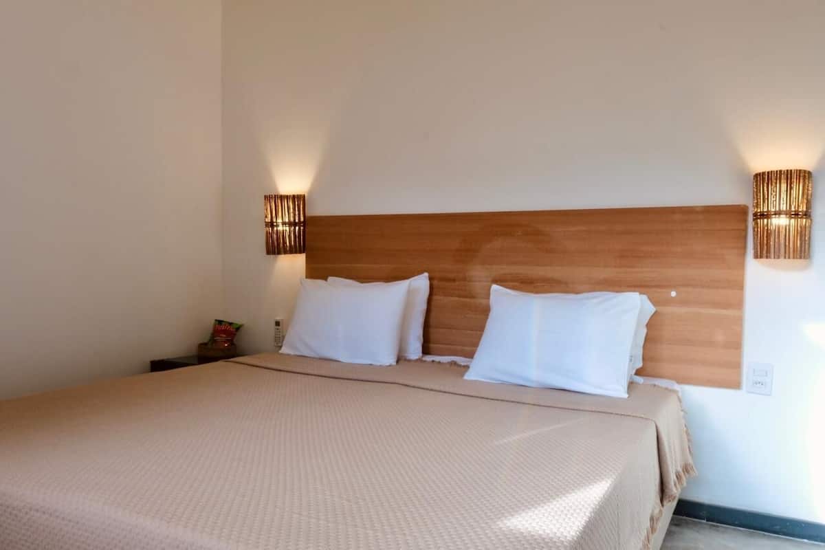 A neatly made bed with a wooden headboard, two white pillows, and a beige bedspread.