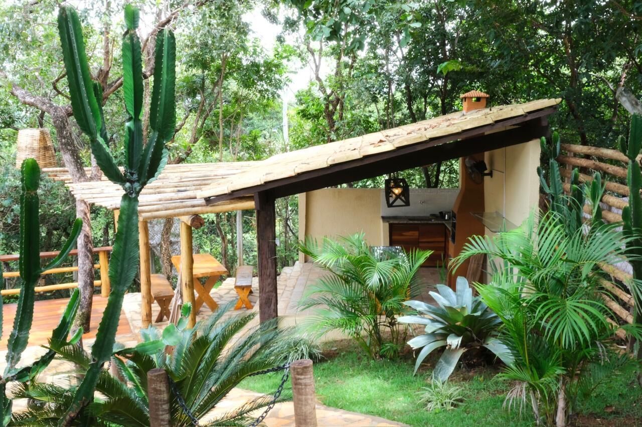 A rustic wooden structure with a thatched roof, surrounded by various cacti and tropical plants.