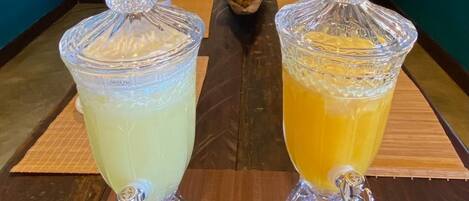 Two glass containers with lids on a wooden table, each with a spoon and napkin.
