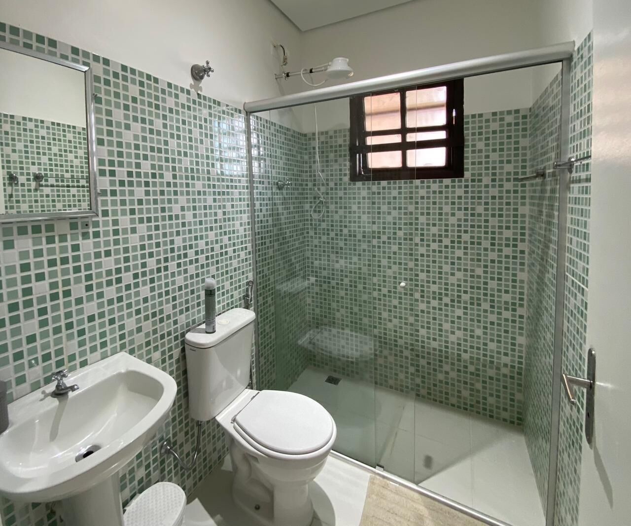 A bathroom with a glass shower enclosure, a toilet, and a sink.