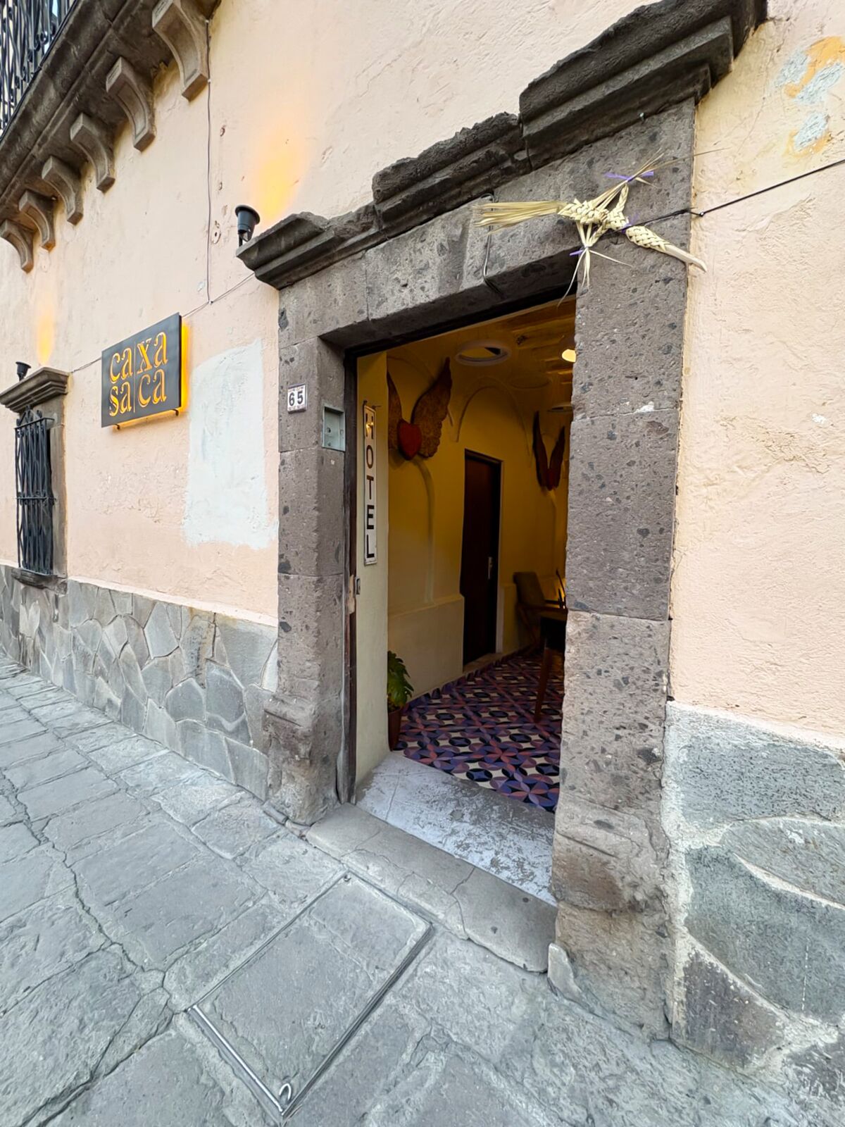 L’entrée d’un hôtel, avec une façade en pierre, une enseigne indiquant « caxa sa ca » et un sol à motifs.