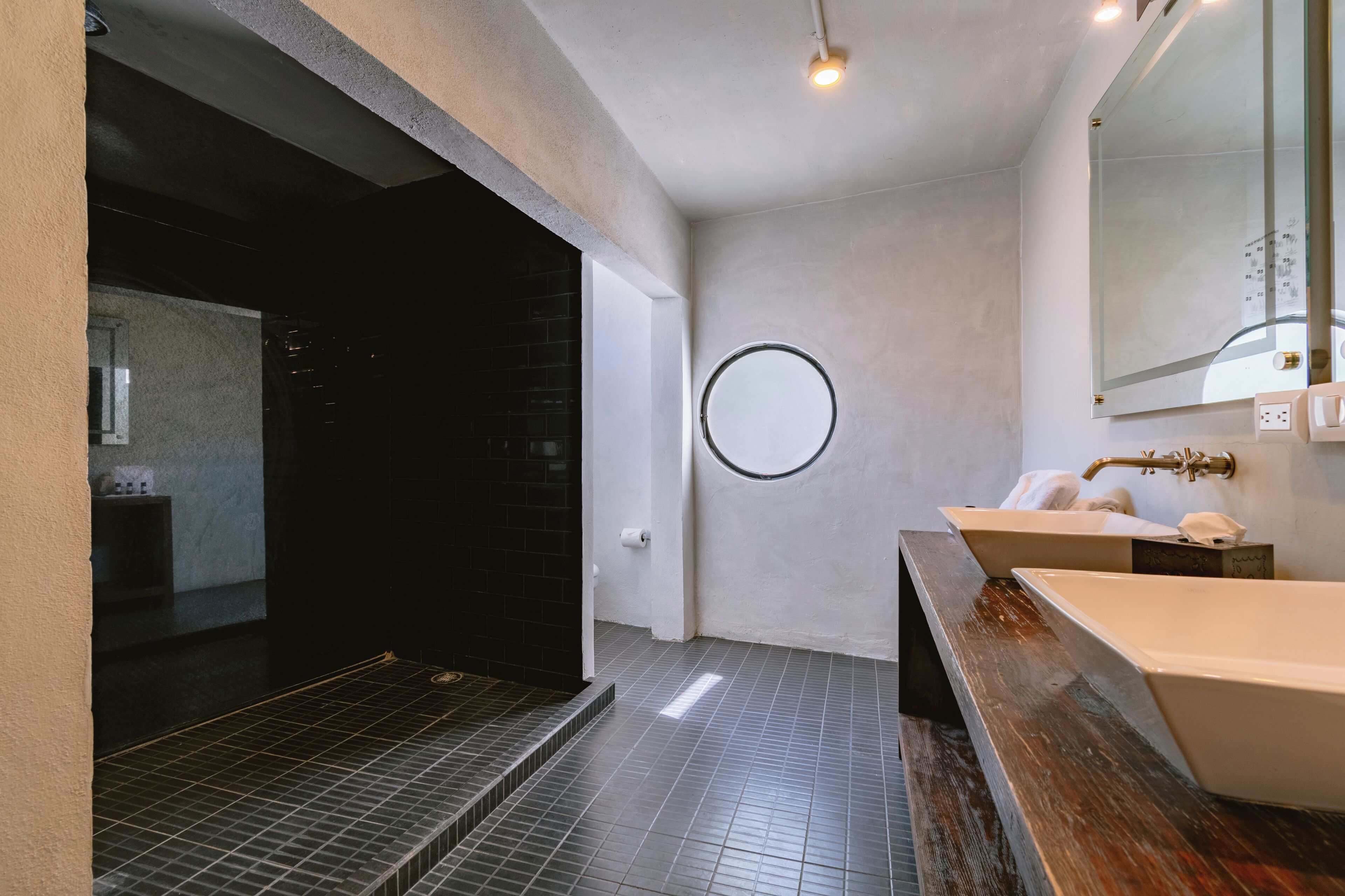 A modern bathroom with a large mirror, two sinks, and a shower area.