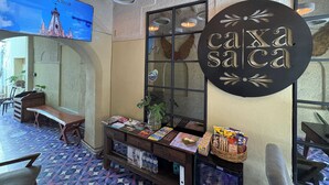 A cozy interior with a 'caxa saça' sign, a TV displaying a cityscape, and a patterned floor. - Casa Xaca (San Miguel de Allende)