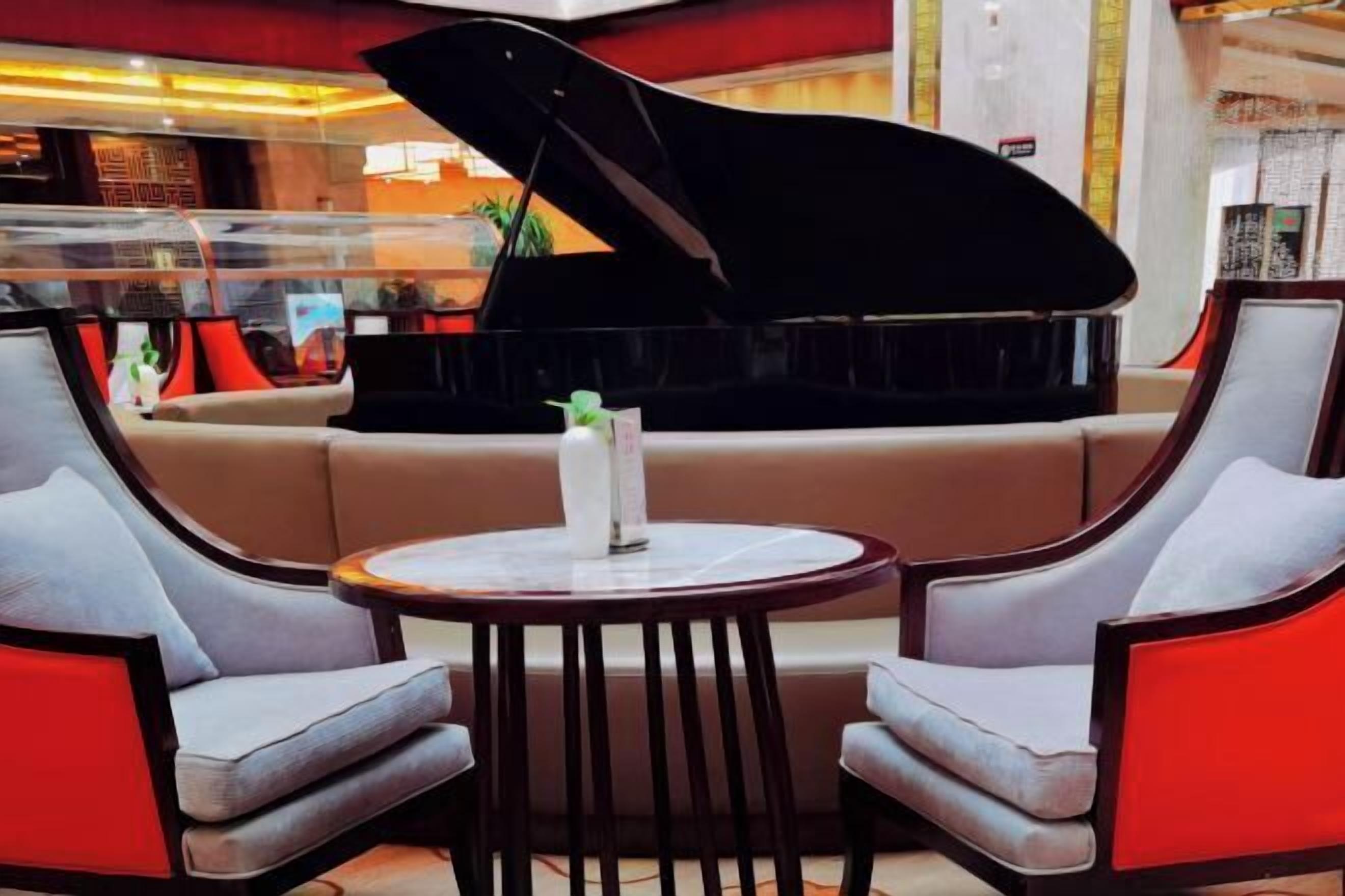 A modern lounge area with a grand piano, comfortable seating, and a small table.