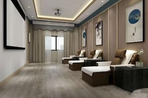 Una habitación de hotel con una cama grande, una zona de estar con sofá y sillones, una mesita y un ventanal con cortinas.