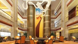 Eine geräumige Lobby mit hohen Decken, großen Säulen und einem zentral platzierten Kunstwerk.