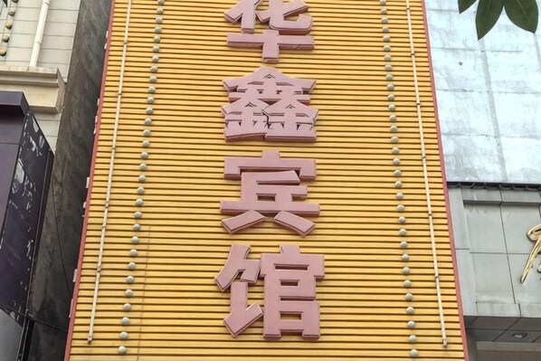 A building facade with a yellow wall and a sign with Chinese characters. - Anxin Huaxin Hotel (Anxin)
