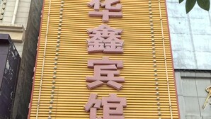 A building facade with a yellow wall and a vertical sign with Chinese characters. - Anxin Huaxin Hotel (Anxin)