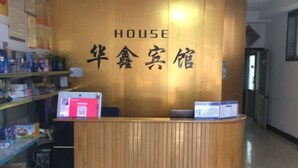 A reception desk with a wooden finish and a sign above it. - Anxin Huaxin Hotel (Anxin)