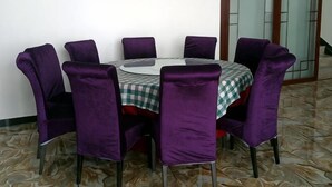 A round dining table with eight purple chairs, a checkered tablecloth, and a tiled floor. - Anxin Huaxin Hotel (Anxin)