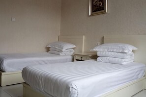 Una camera d'albergo con due letti singoli, un comodino e un quadro appeso al muro.