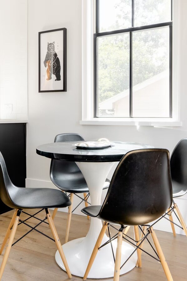 A modern dining area with a round table, black chairs, and a white pedestal base.