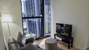 A modern living room with a sofa, ottoman, and a television on a stand. - Melbourne CBD Southern Cross City View Retreat (Melbourne)