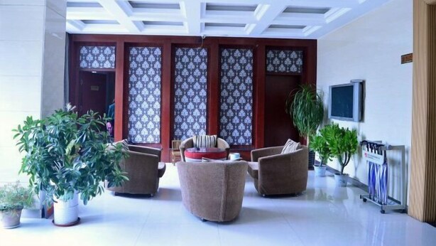 Um hall de entrada com design de teto moderno, área de estar com sofás e plantas em vasos.