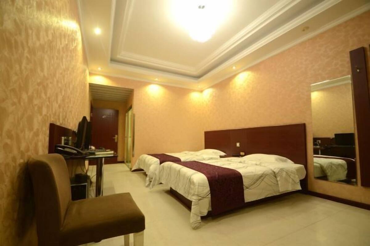 A hotel room with two beds, a desk with a computer, and a chair.