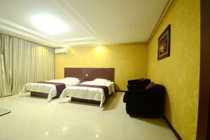 Een hotelkamer met twee bedden, een donkere koffer en een ingelijste foto aan de muur.
