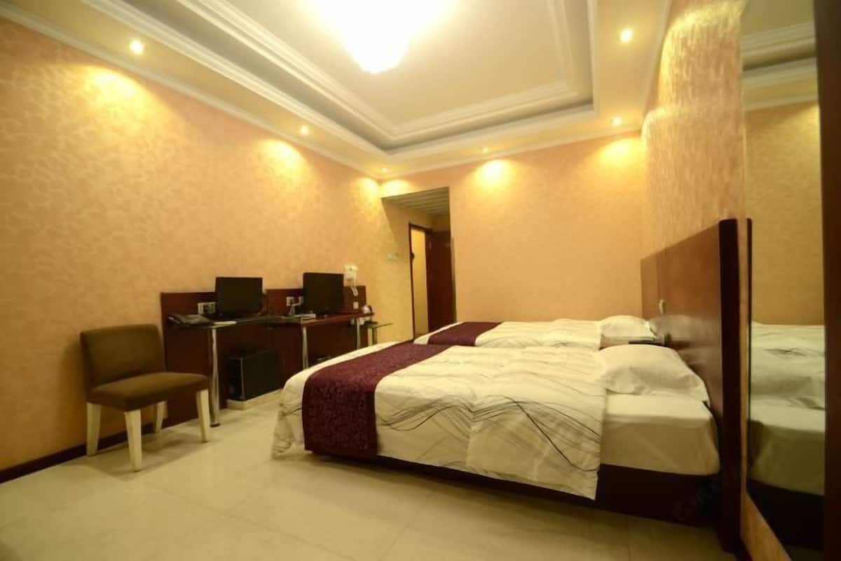 A hotel room with two beds, a desk with a computer, and a chair.