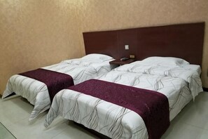 Ein Doppelbett mit Kopfteil, zwei Nachttische und eine violette Tagesdecke.