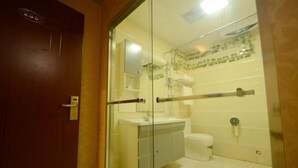 Casa de banho com divisória de vidro, lavatório branco, sanita e zona de duche.