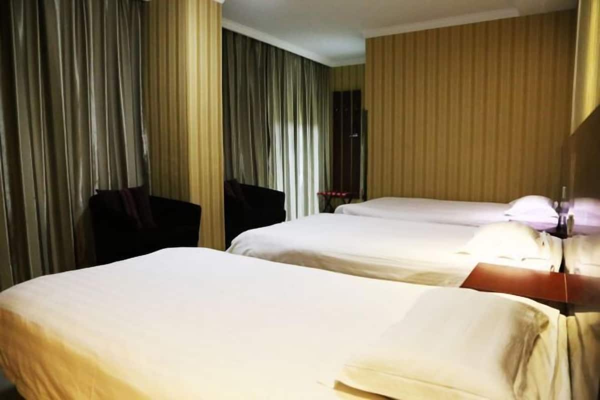 A hotel room with two beds, a wooden headboard, and a curtain on one side.