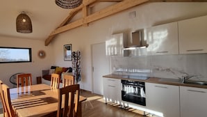 A modern kitchen with white cabinets, a built-in oven, and a large window. - Gite facing the Vercors (Marches)