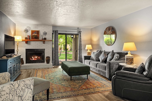 Cozy living room with fireplace, stylish seating, and backyard views through sliding doors.