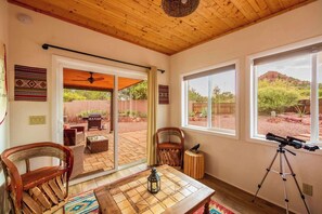 A room with a patio area, a telescope, and a view of the desert landscape.
