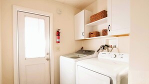 A laundry room with a washing machine, dryer, and a fire extinguisher on the wall.