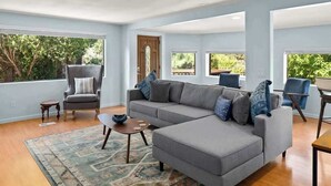 A spacious living room with a grey sectional sofa, a small round coffee table, and a patterned rug.