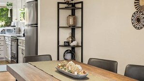 Una cocina moderna con una mesa de comedor de madera, sillas negras e iluminación colgante.