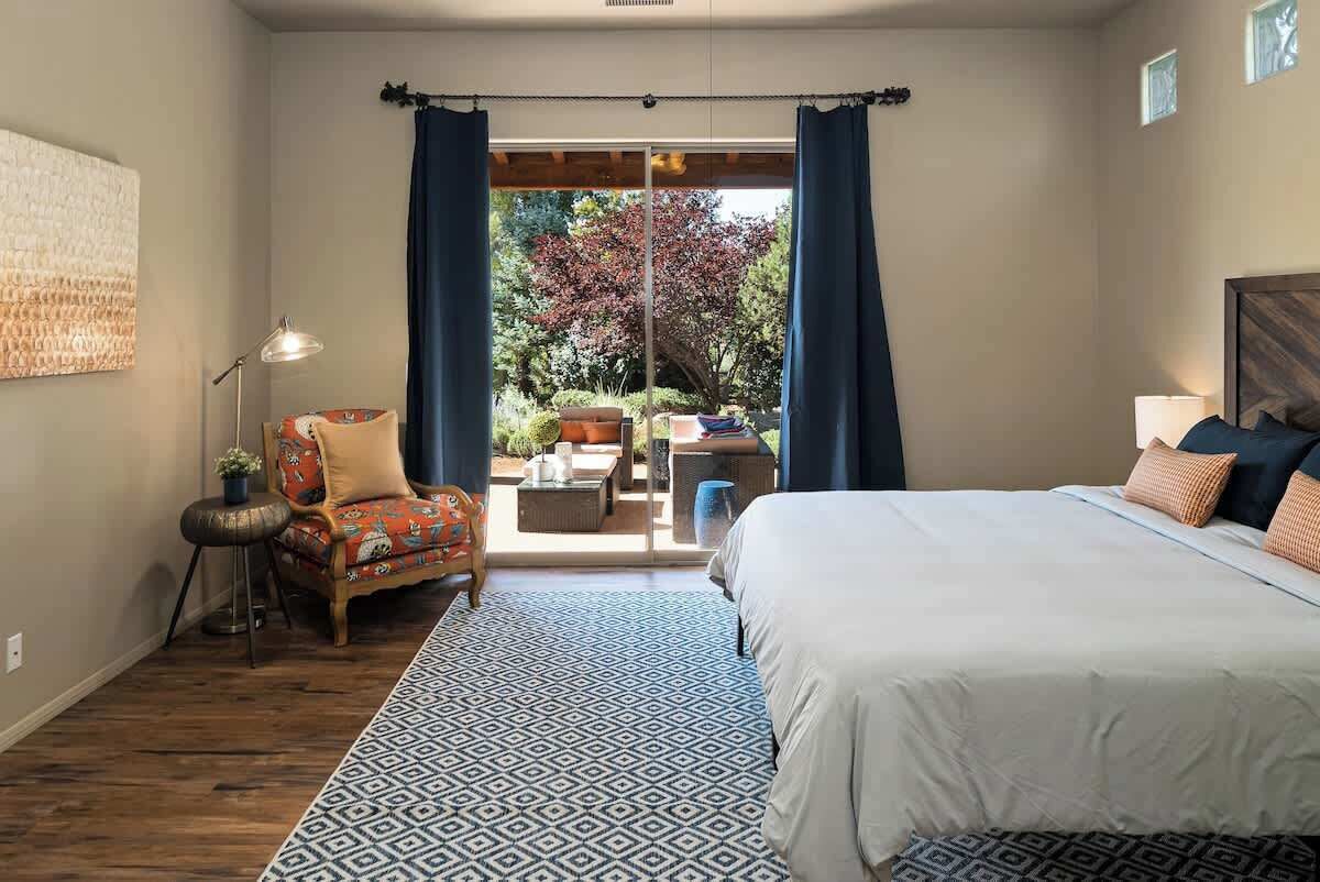 Een slaapkamer met een groot bed, een stoel, een bureau en uitzicht op de omgeving.